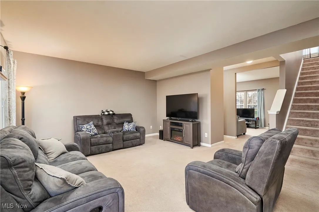 Living room with carpet, stairs, an open space with stairs to upstairs.