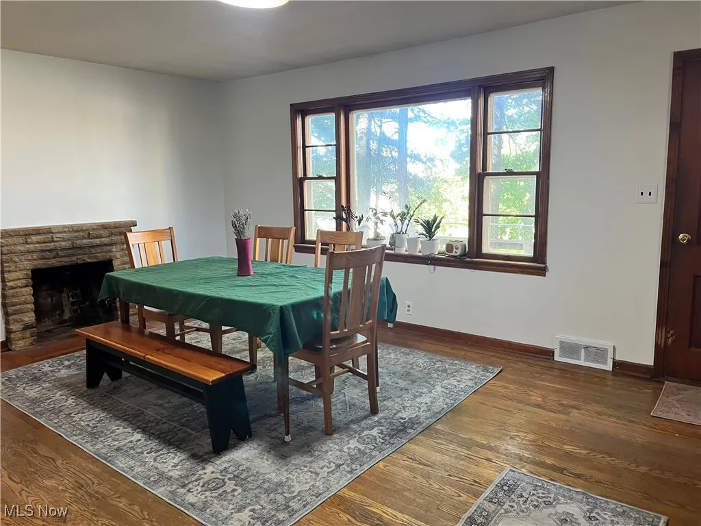 Dining room featuring a brick fireplace and dark wood-style flooring