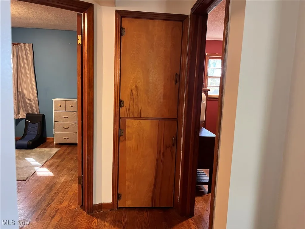 Corridor with dark wood-style flooring and a textured ceiling