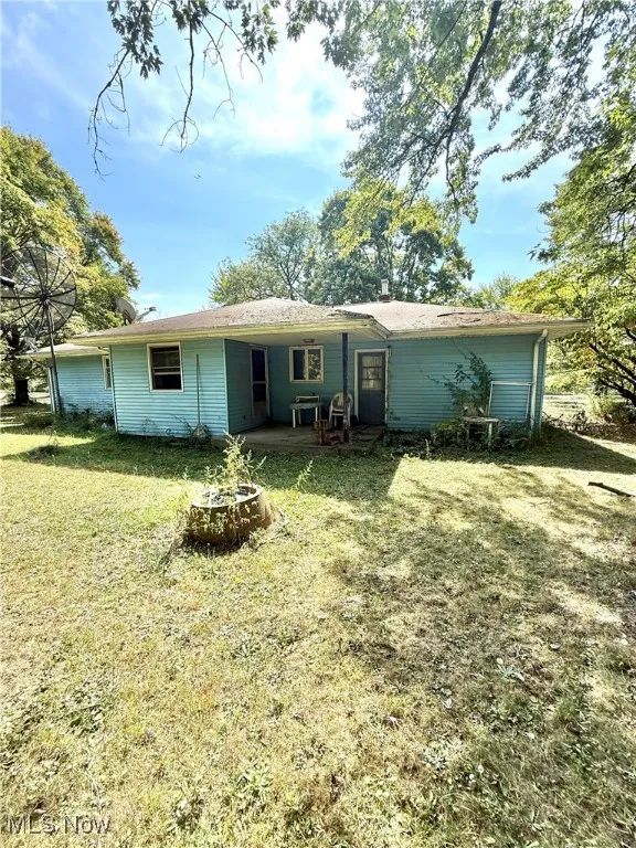 View of front of home with a fire pit, a patio, and a front lawn