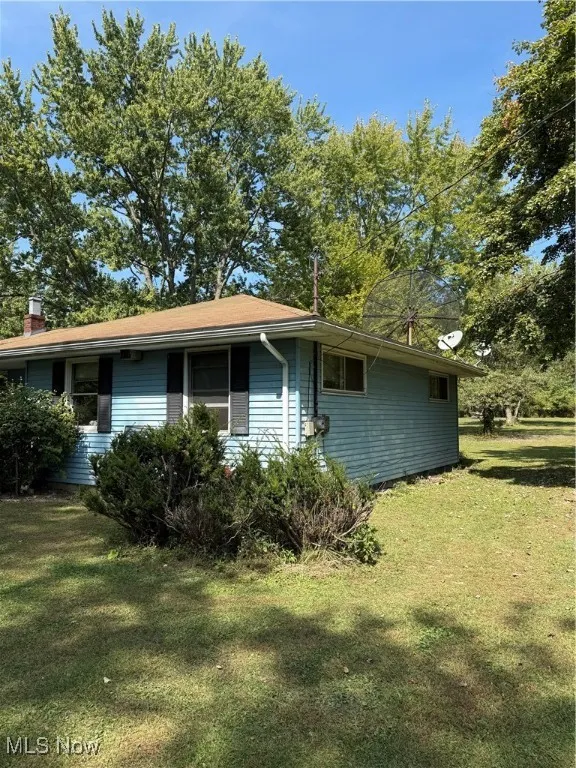 View of side of home with a yard and a chimney