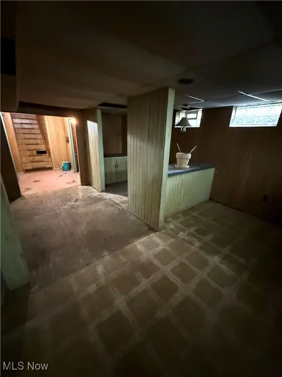 Basement with wooden walls, stairs, and a drop ceiling