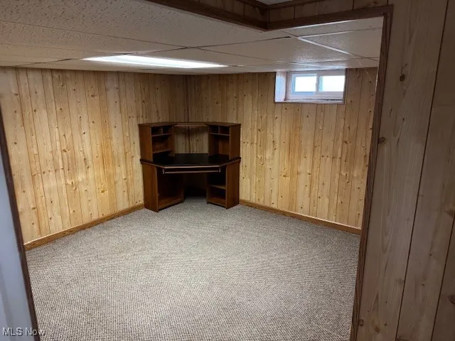 Unfurnished office featuring wooden walls, carpet floors, and a drop ceiling