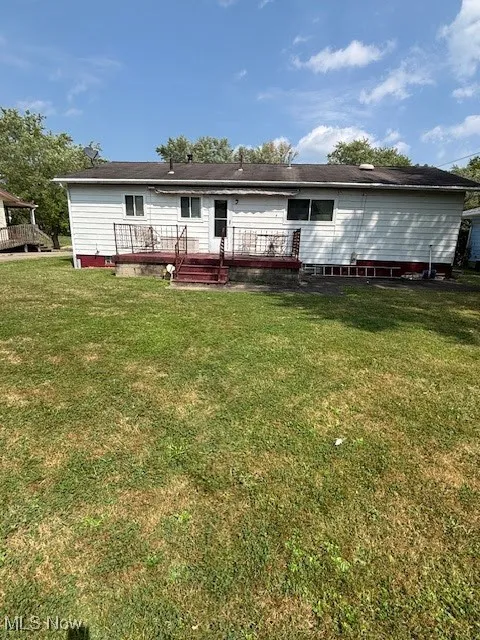Rear view of property featuring a lawn, a wooden deck, and crawl space