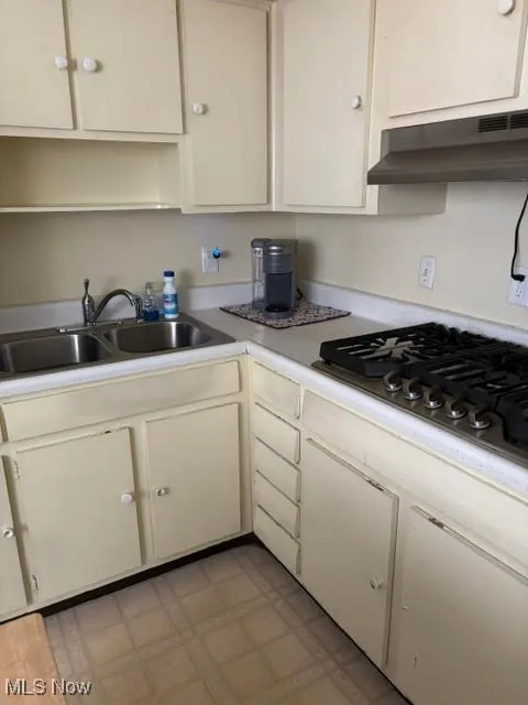 Kitchen featuring light countertops, gas cooktop, under cabinet range hood, and white cabinets