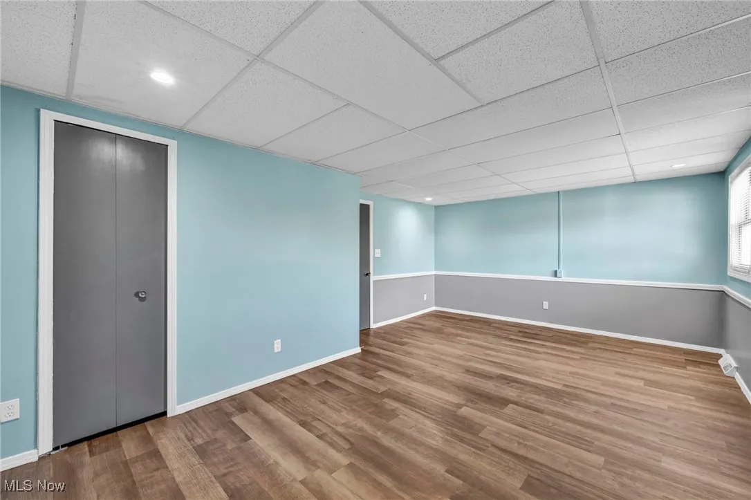 Below grade area with wood finished floors, a drop ceiling, and recessed lighting