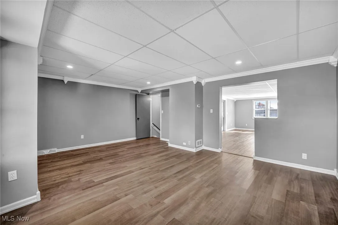 Basement with wood finished floors, recessed lighting, ornamental molding, and a paneled ceiling