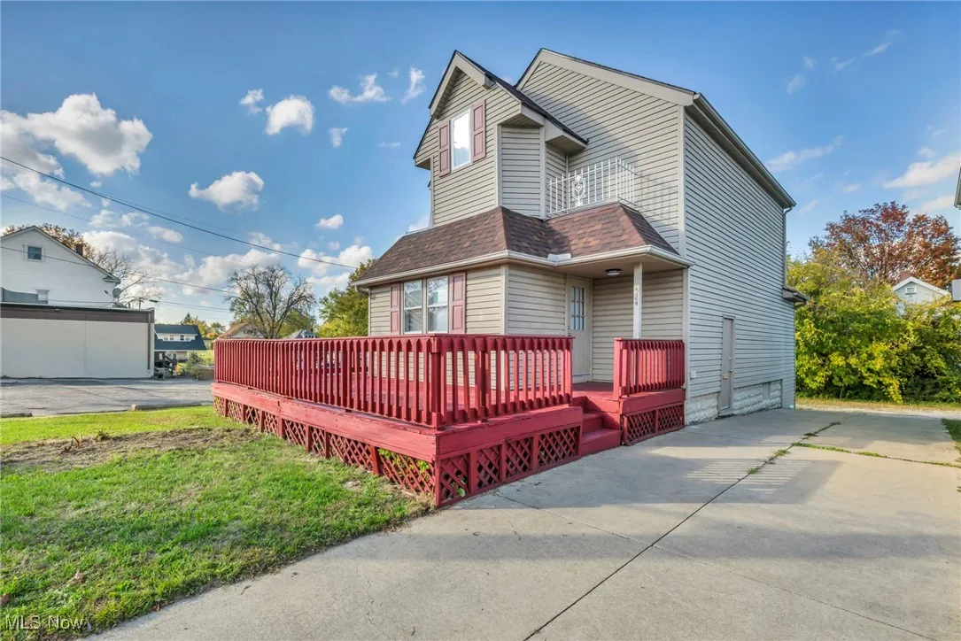 View of home's exterior with a deck, a shingled roof, a balcony, and a yard
