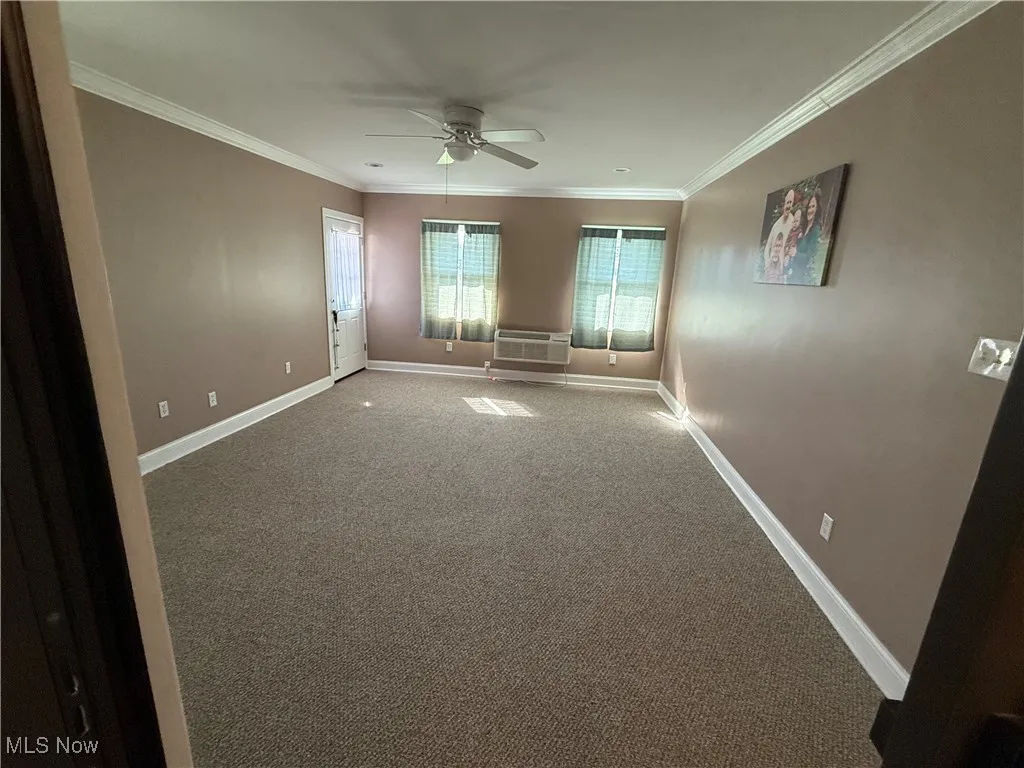 Unfurnished room with carpet floors, ornamental molding, and a ceiling fan
