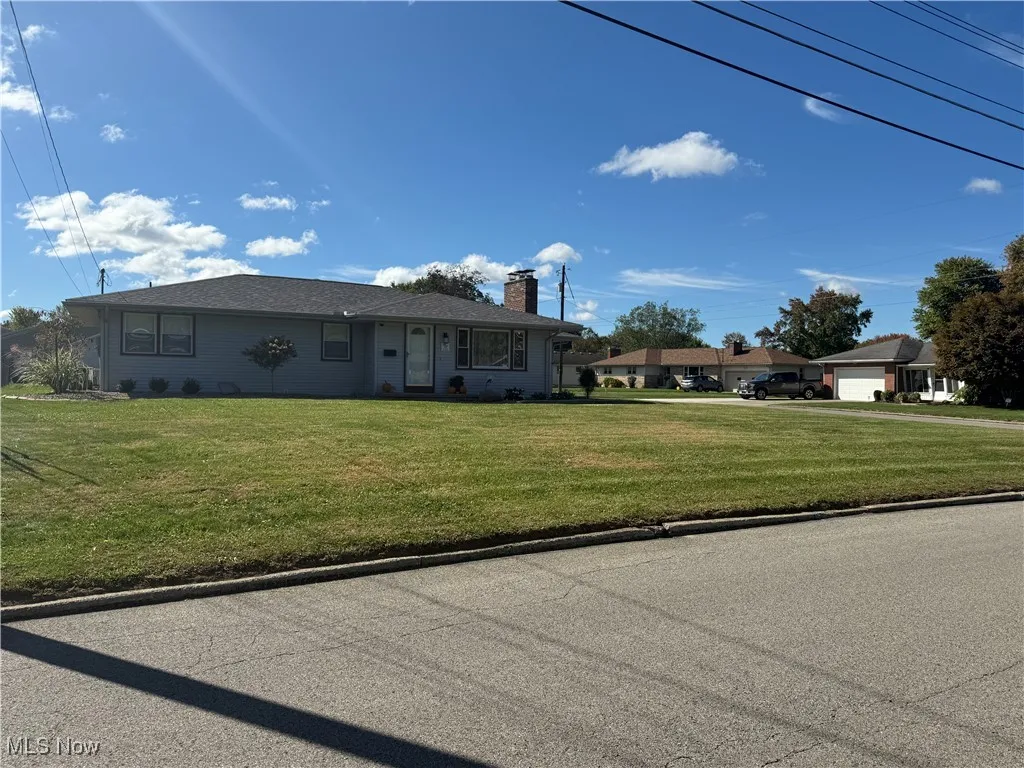 Single story home featuring a chimney and a front lawn