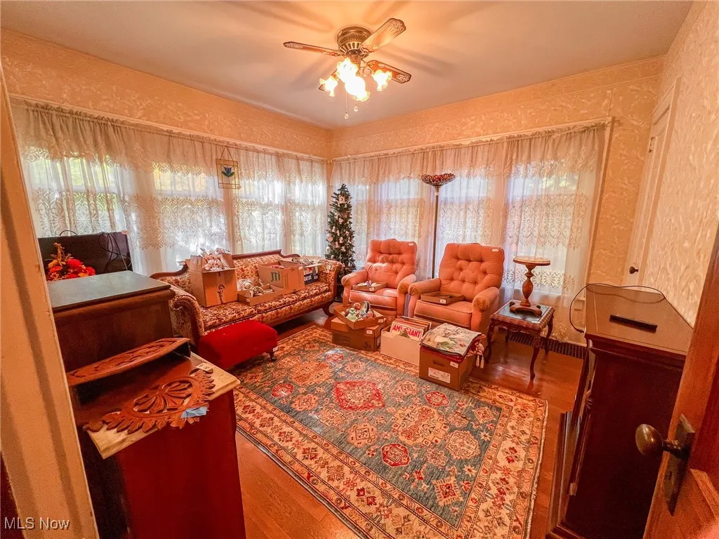 Living area with wood finished floors, wallpapered walls, and ceiling fan