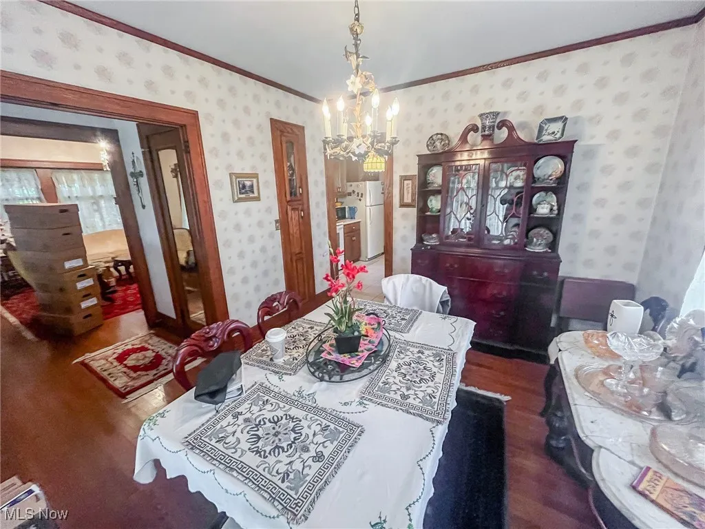 Dining space featuring ornamental molding, a chandelier, dark wood-style flooring, and baseboard heating