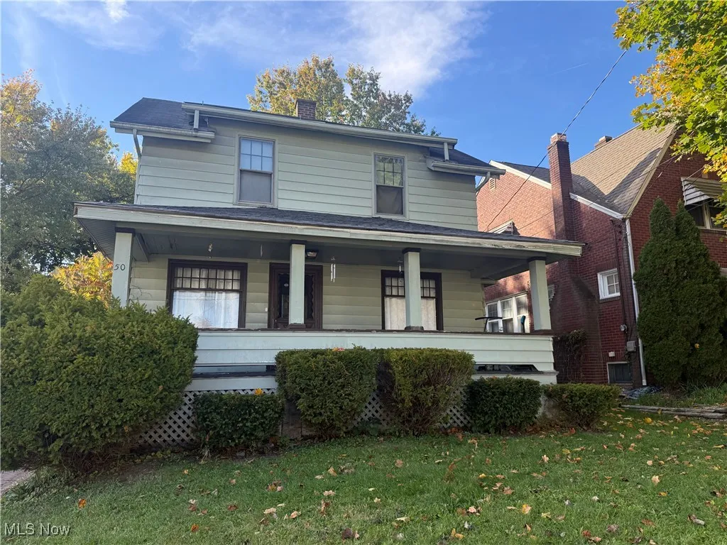 View of front facade with a porch, a front lawn, and a chimney