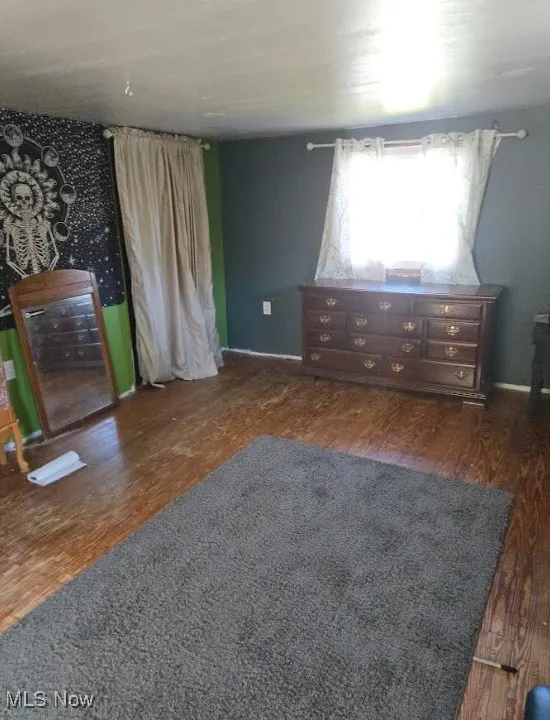 Unfurnished bedroom featuring dark wood-style floors and baseboards