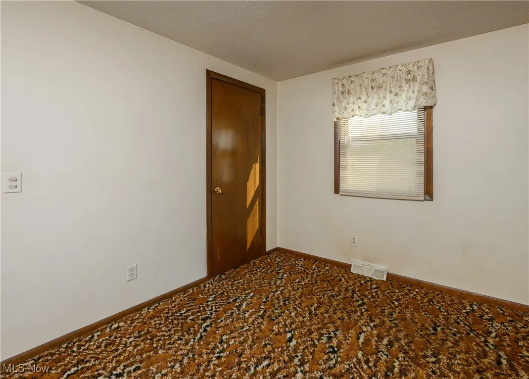 Unfurnished room with a textured ceiling and baseboards