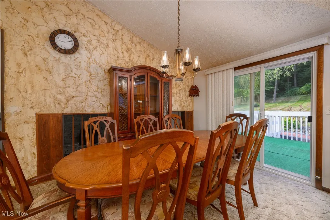 Dining space with a chandelier, a textured ceiling, and lofted ceiling