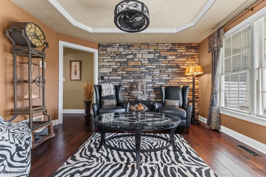 Living area featuring dark wood-type flooring, a tray ceiling, and a textured ceiling