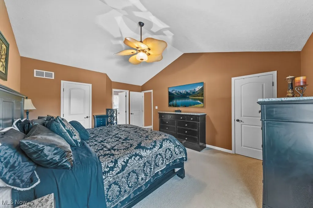 Bedroom featuring vaulted ceiling, light colored carpet, and ceiling fan