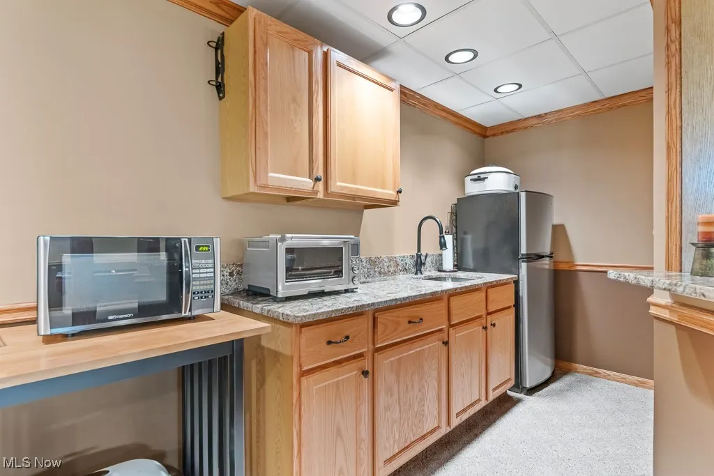 Kitchen featuring light brown cabinets, appliances with stainless steel finishes, light stone countertops, recessed lighting, and ornamental molding