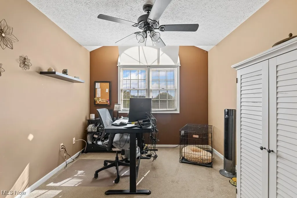 Bedroom featuring a textured ceiling, light colored carpet, vaulted ceiling, and ceiling fan