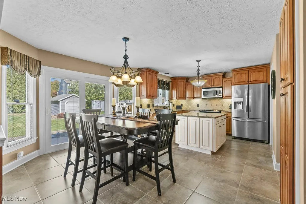 Dining room with a textured ceiling, light tile patterned flooring, and a chandelier