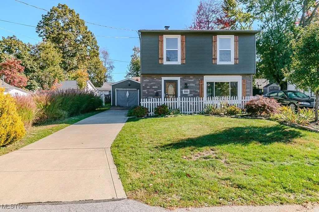 Colonial house with driveway, stone siding, and an outdoor structure