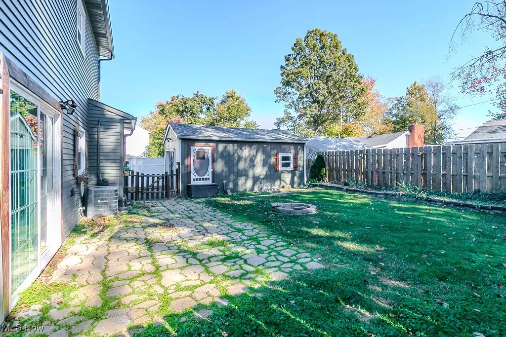 Fenced backyard featuring an outdoor structure, a fire pit, and a patio