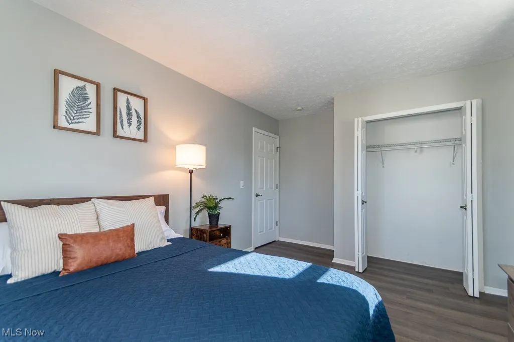 Bedroom featuring a textured ceiling, dark wood-type flooring, and a closet