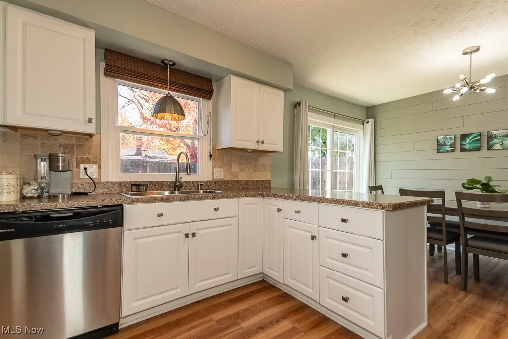 Kitchen featuring stainless steel dishwasher, a textured ceiling, a peninsula, white cabinetry, and light wood-type flooring