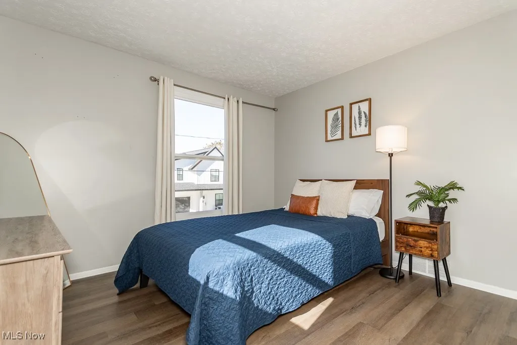 Bedroom with a textured ceiling and dark wood-style floors