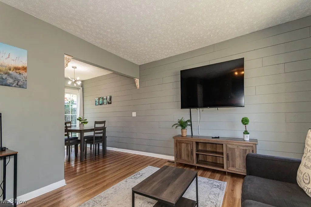 Living area featuring a textured ceiling, wood finished floors, wood walls, and a chandelier