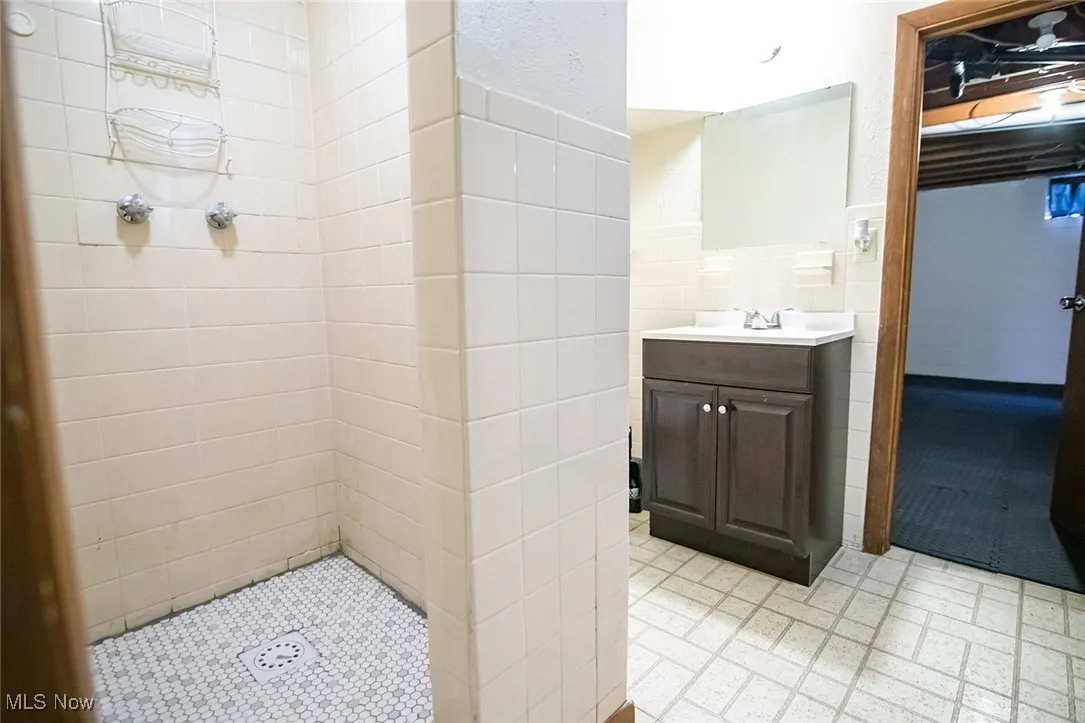 Full bath with tile walls, vanity, and tiled shower
