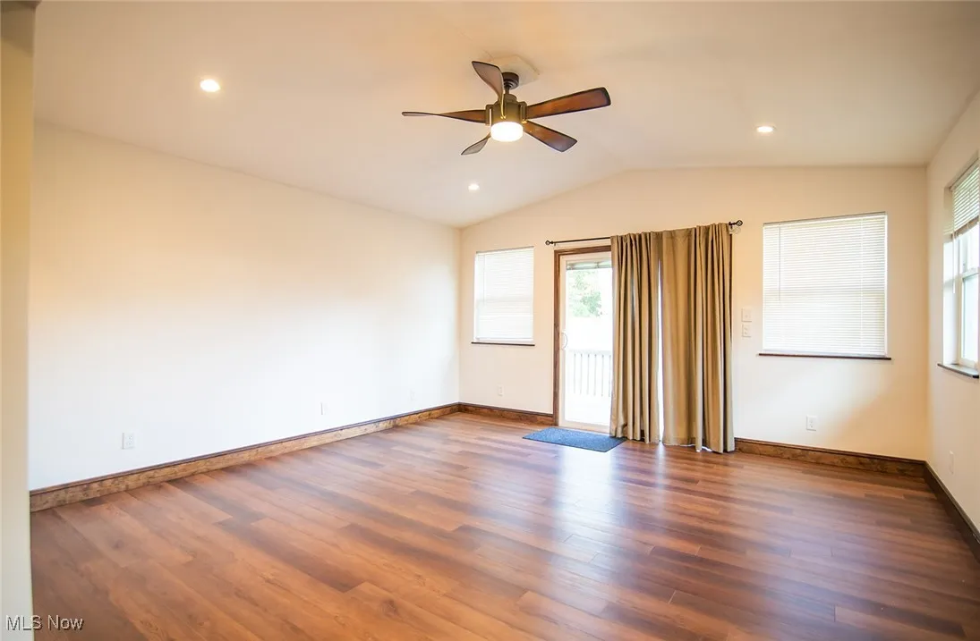 Unfurnished room with plenty of natural light, wood finished floors, vaulted ceiling, a ceiling fan, and recessed lighting