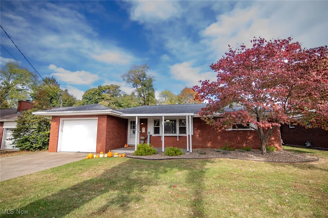 Ranch-style house featuring a porch, a front yard, a garage, concrete driveway, and brick siding