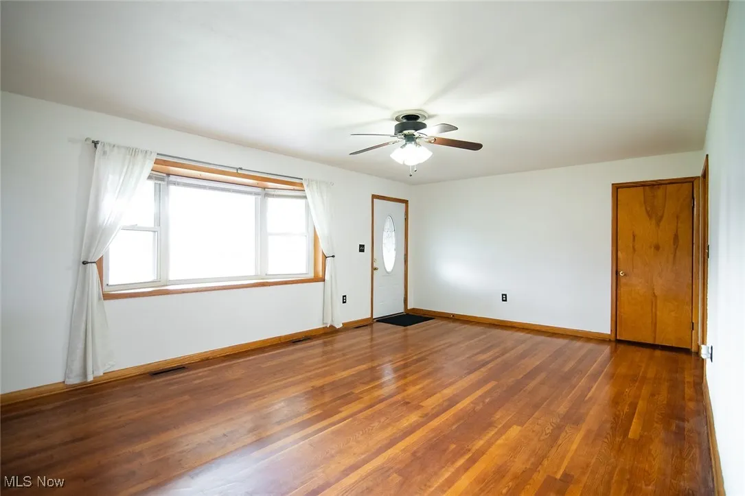 Empty room with wood finished floors and a ceiling fan