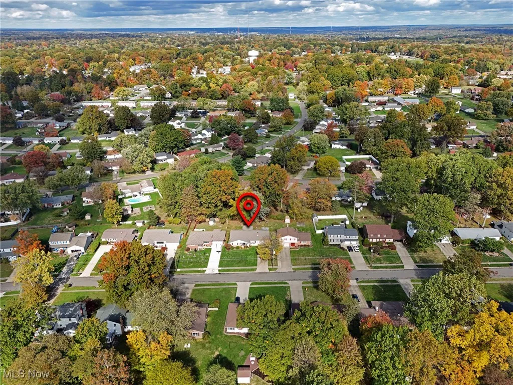 Aerial view of property and surrounding area featuring nearby suburban area and a tree filled landscape