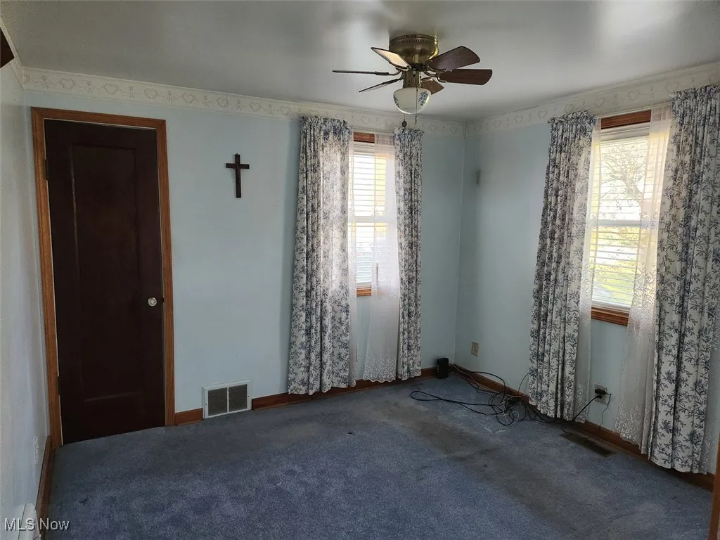 Carpeted spare room with ceiling fan and ornamental molding