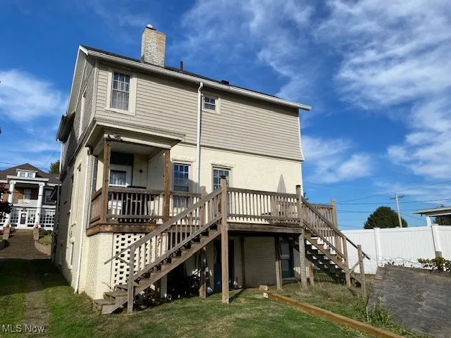 Back of property with stairs, a deck, a yard, and a chimney