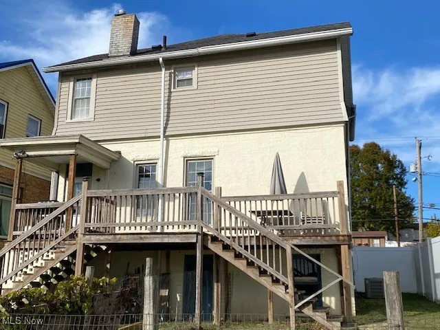 Back of house featuring a wooden deck, stairs, and a chimney