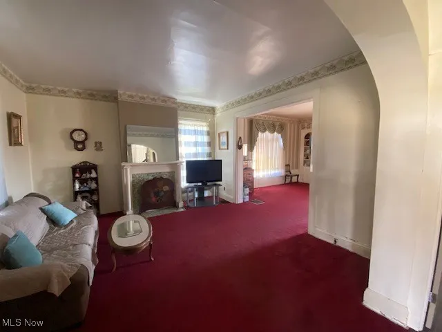 Carpeted living room featuring arched walkways and baseboards