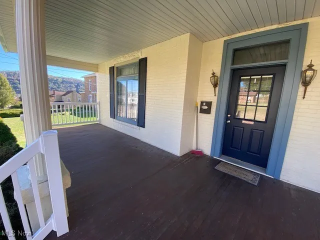 Doorway to property featuring covered porch and brick siding
