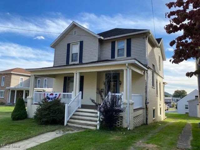 View of front of property featuring a porch, brick siding, and a front lawn