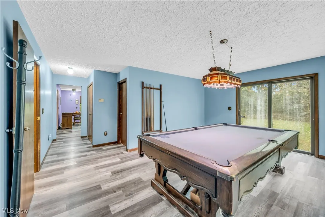 Game room featuring billiards, a textured ceiling, and light wood finished floors