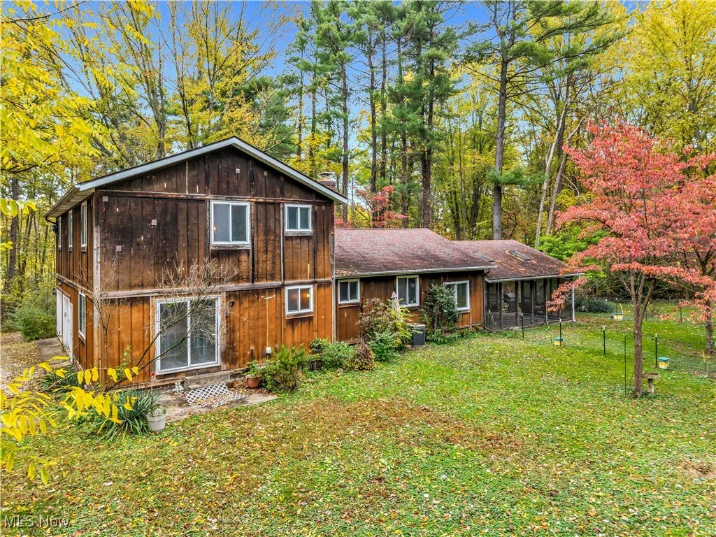 Rear view of property with entry steps and view of wooded area