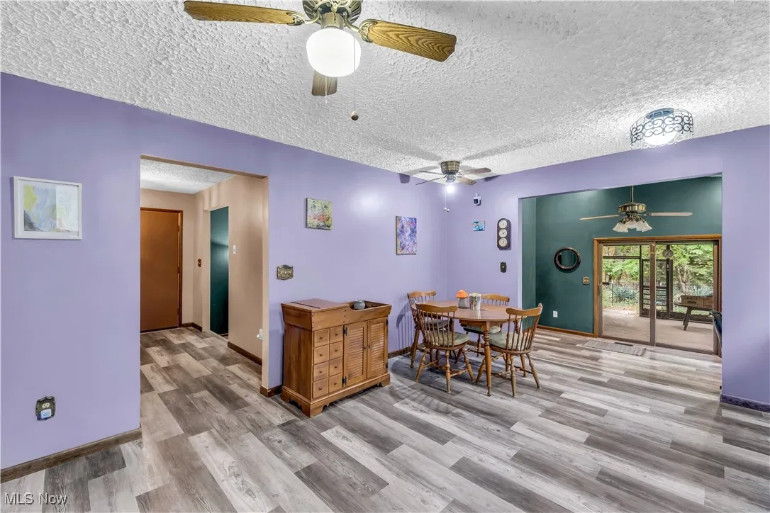 Dining space featuring a textured ceiling, light wood-type flooring, and a ceiling fan