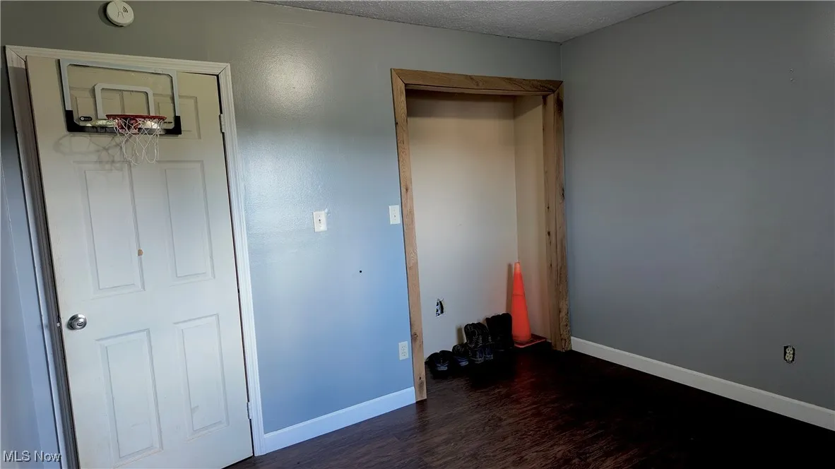 Unfurnished bedroom featuring dark wood finished floors and a textured ceiling