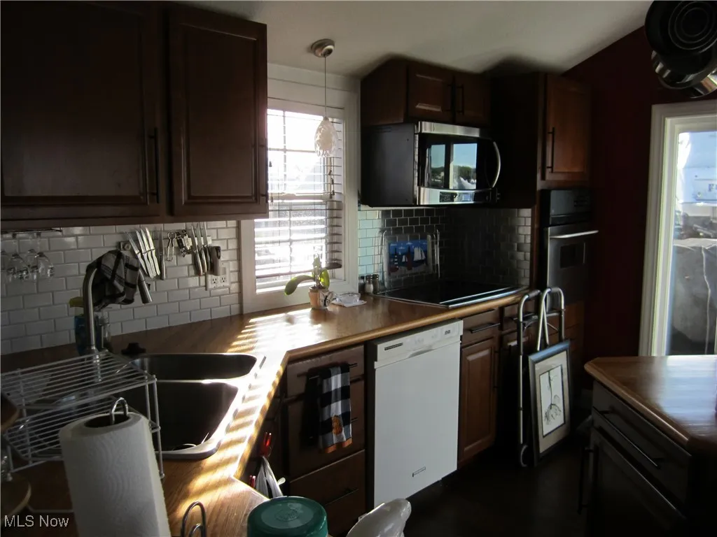 Kitchen featuring plenty of natural light, appliances with stainless steel finishes, decorative backsplash, and hanging light fixtures