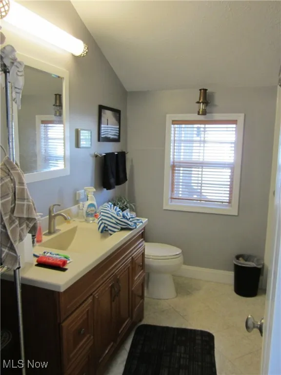 Bathroom with vanity, light tile patterned floors, and lofted ceiling