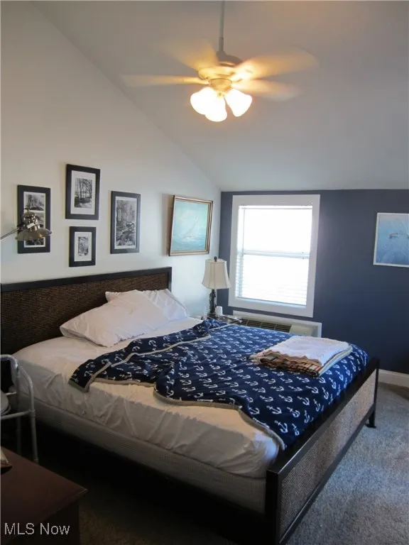 Carpeted bedroom featuring lofted ceiling and a ceiling fan