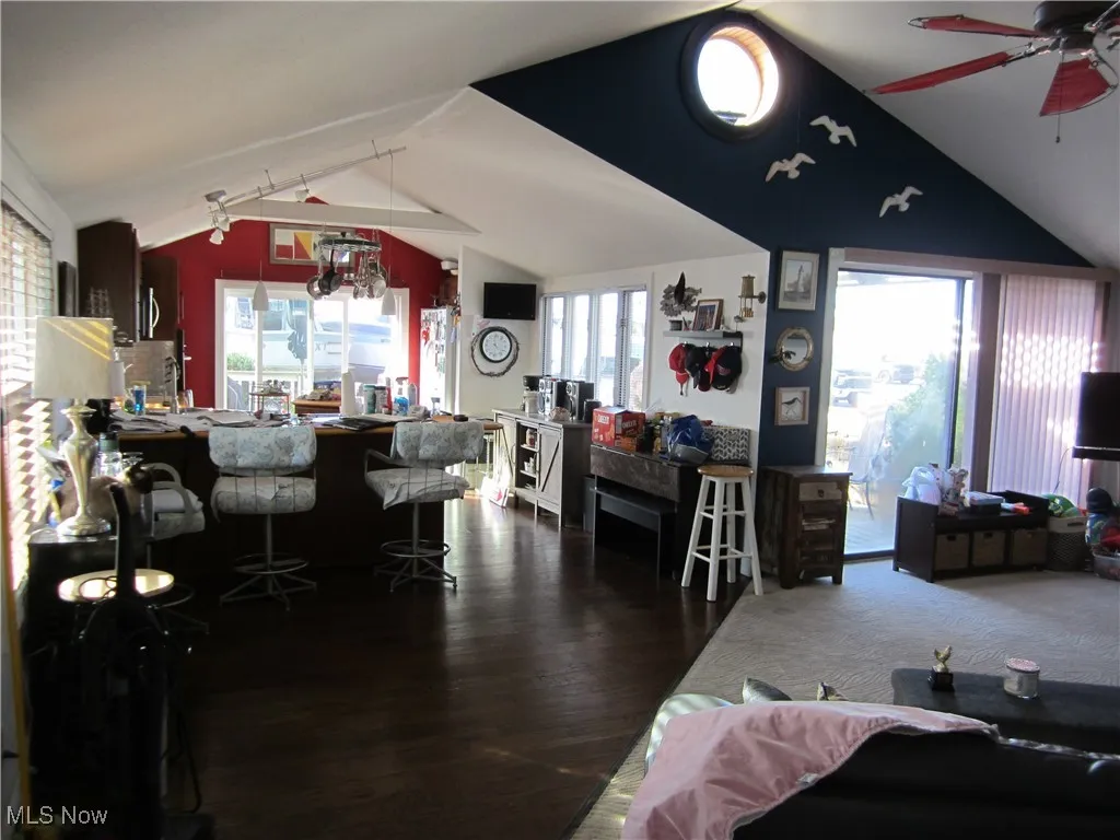 Living area featuring vaulted ceiling, a ceiling fan, dark wood finished floors, and a chandelier
